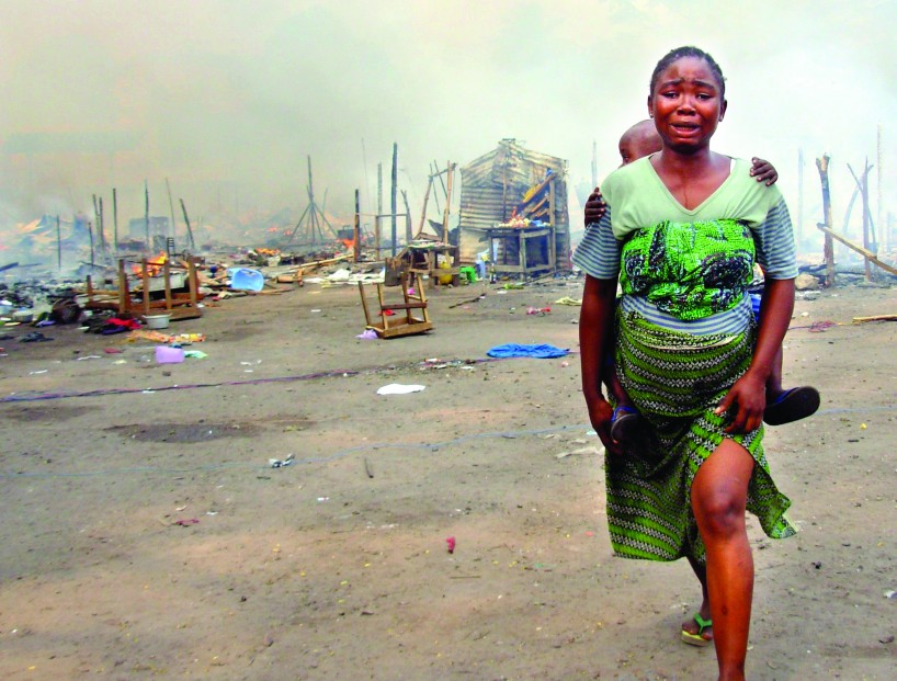 Woman and child run from burning compound of bodyguards of a presidential candidate, Kinshasa DRC. Photo: Eddy Isango/IRIN